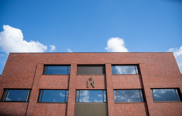 Een foto van de ingang van het gebouw van Midwerk in Sappemeer, waar Talentperron is gevestigd. Het is een gebowu met rode bakstenen en het Midwerk logo boven de ingang.